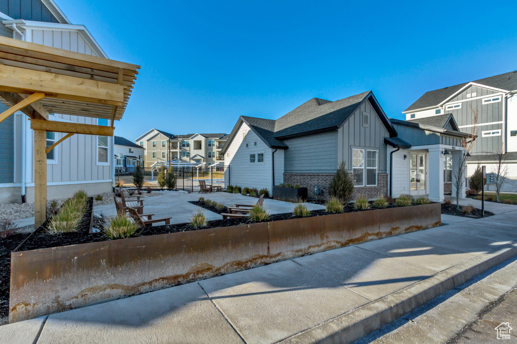 View of property exterior with board and batten siding, a residential view, brick siding, fence, and roof with shingles