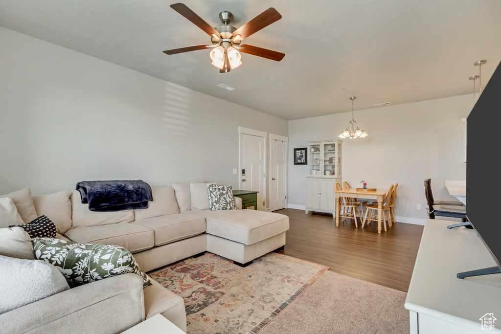 Living area featuring a chandelier, a ceiling fan, baseboards, and wood finished floors