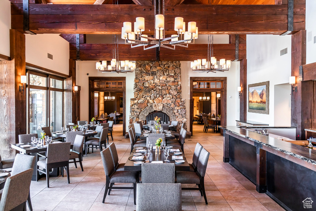 Dining space with a chandelier, beam ceiling, a towering ceiling, and light tile patterned floors