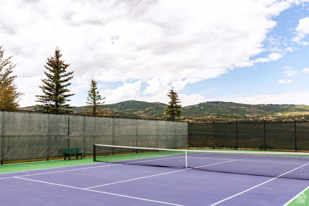 View of tennis court with community basketball court, a mountain view, and fence