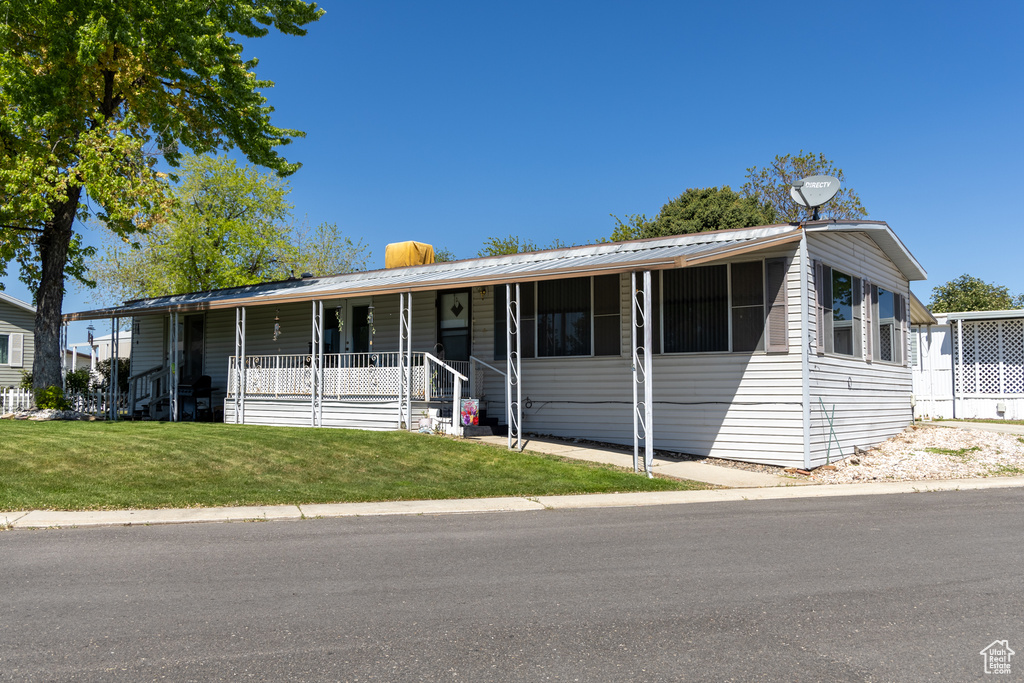 Manufactured / mobile home with a porch, a front lawn, and metal roof