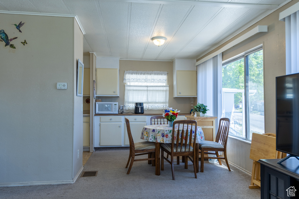 Dining room featuring light carpet, baseboards, and crown molding