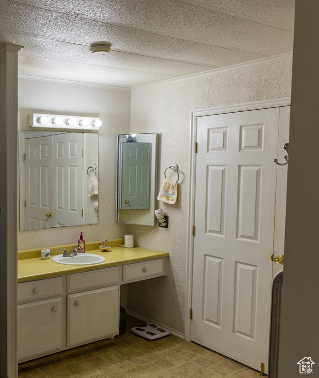 Bathroom featuring vanity, a textured ceiling, and a textured wall