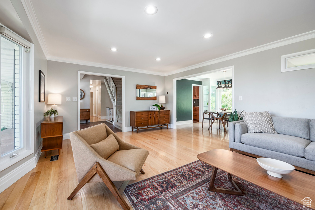 Living room featuring ornamental molding, light wood-style floors, baseboards, recessed lighting, and stairway