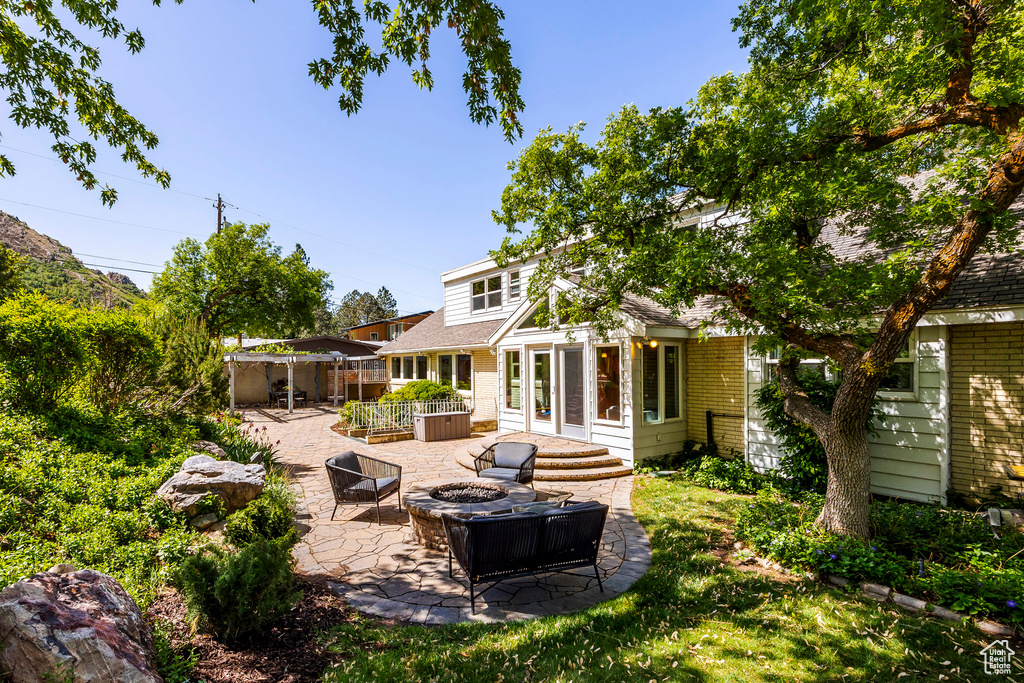 Rear view of house with a fire pit, a patio, brick siding, and fence