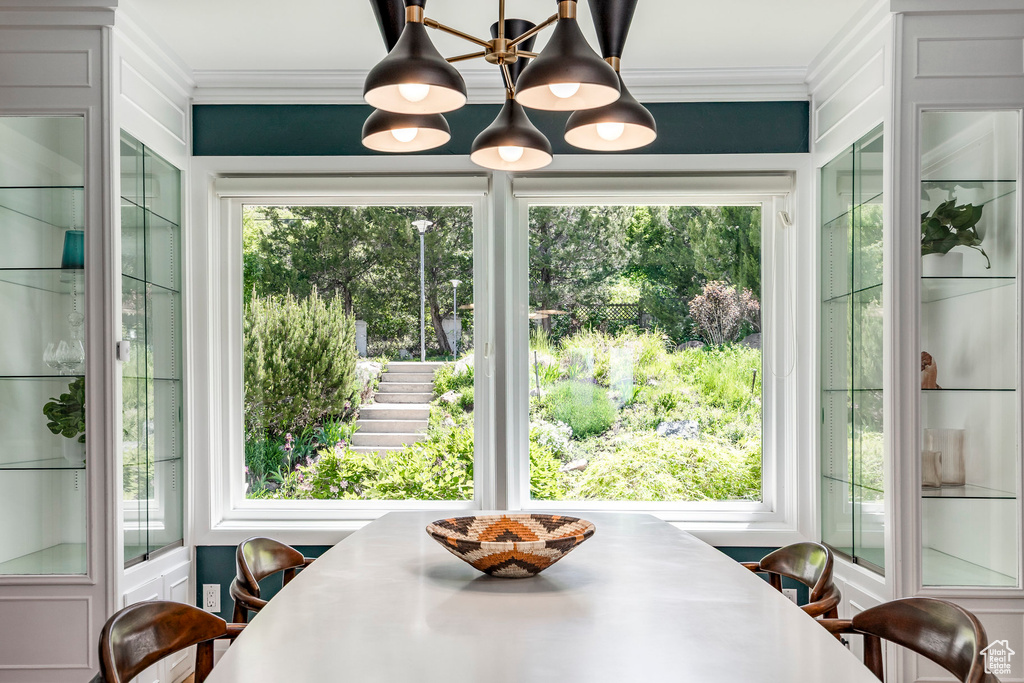 Dining space with ornamental molding, a chandelier, and healthy amount of natural light
