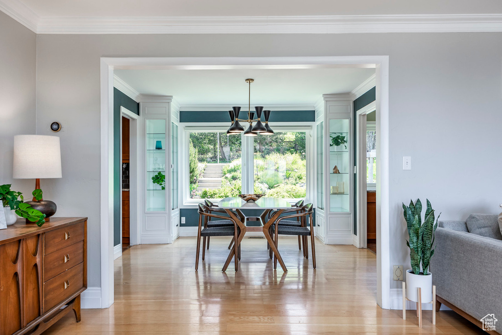 Dining room with a chandelier, crown molding, light wood-type flooring, and baseboards