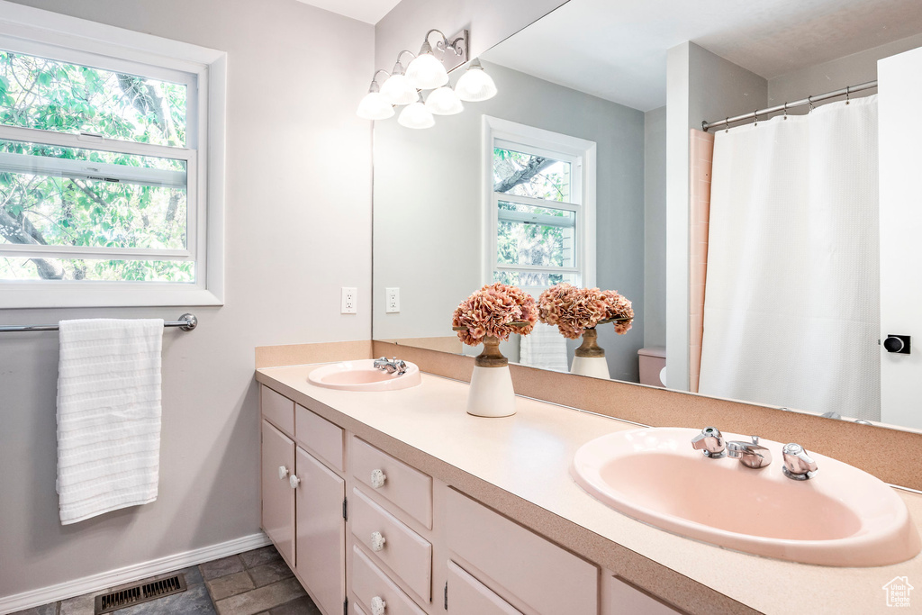 Full bath featuring double vanity, baseboards, toilet, and a shower with shower curtain