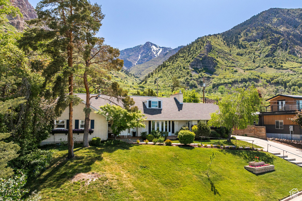 View of front facade featuring a mountain view, a front lawn, and brick siding