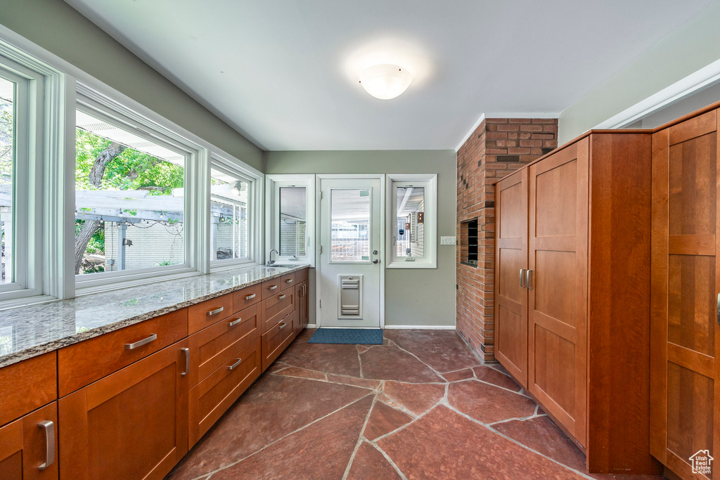 Bathroom featuring brick wall, heating unit, vanity, stone finish floors, and baseboards