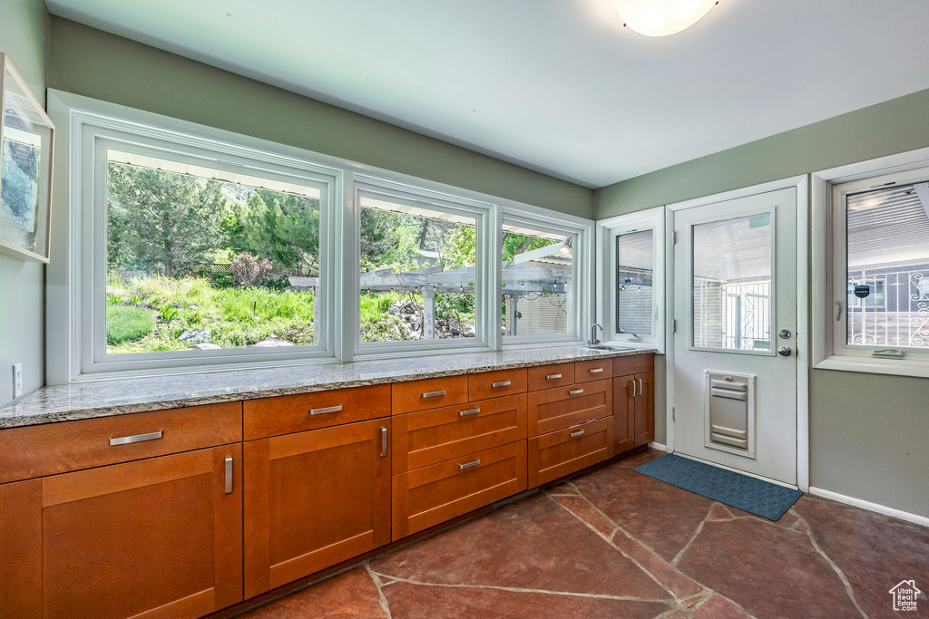 Kitchen with light stone counters, brown cabinetry, and a sink