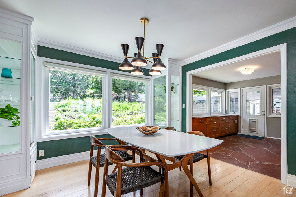 Dining space featuring a chandelier, crown molding, plenty of natural light, and wood finished floors
