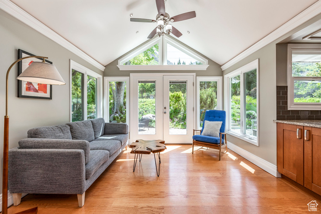 Living room with healthy amount of natural light, light wood-style flooring, a ceiling fan, vaulted ceiling, and baseboards