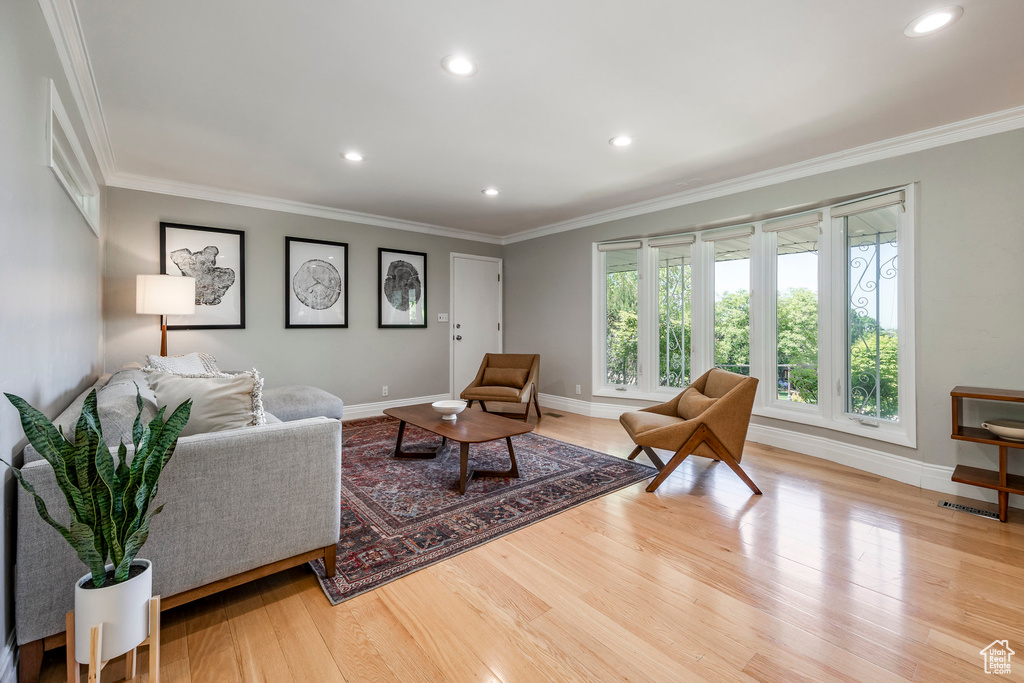 Living room with baseboards, ornamental molding, wood finished floors, and recessed lighting