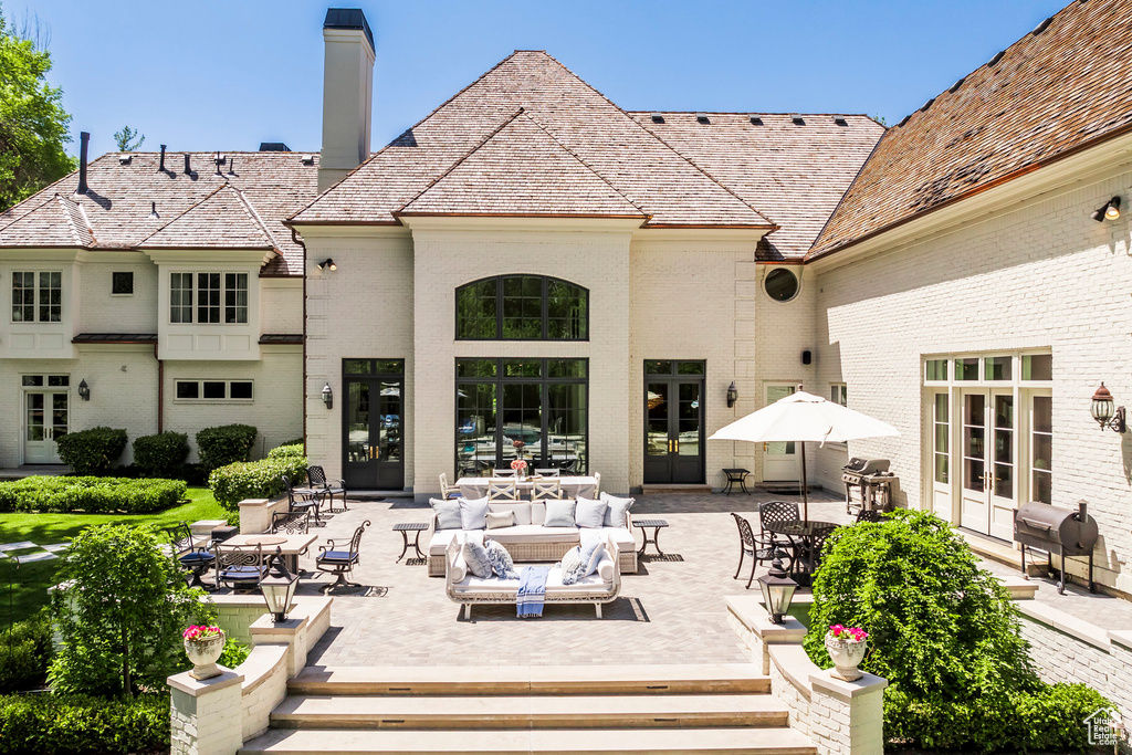 Back of property with french doors, brick siding, a chimney, and a patio area