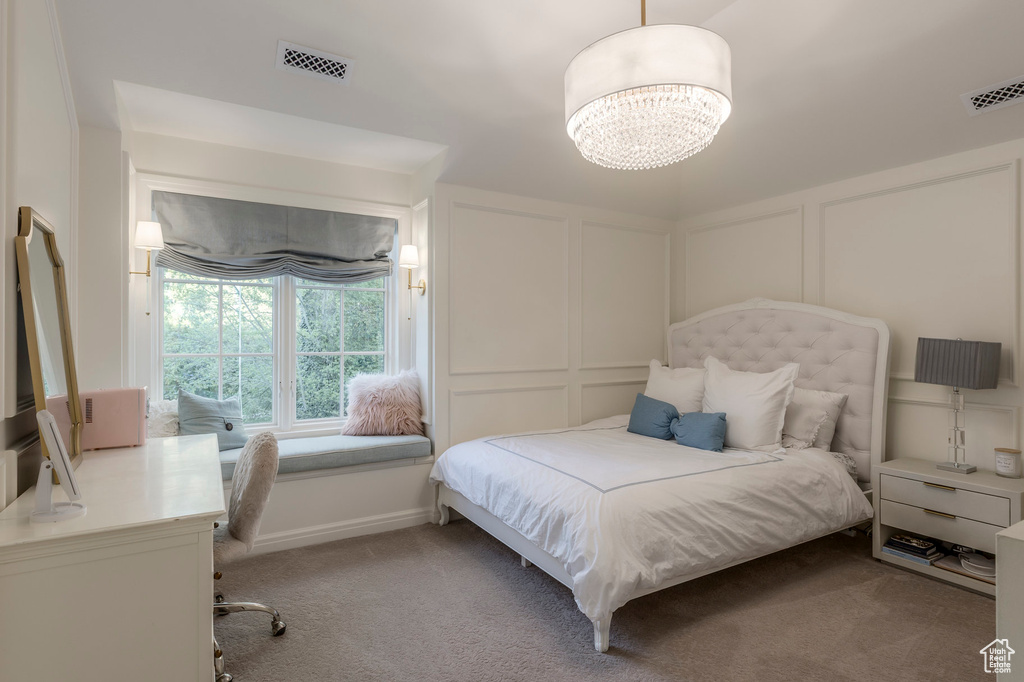 Carpeted bedroom with a decorative wall, a desk, and a chandelier