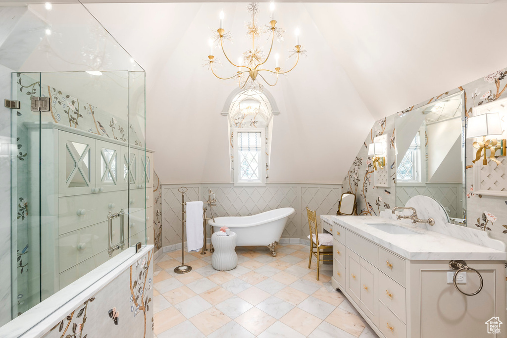 Full bathroom with a chandelier, healthy amount of natural light, a wainscoted wall, a freestanding tub, and lofted ceiling