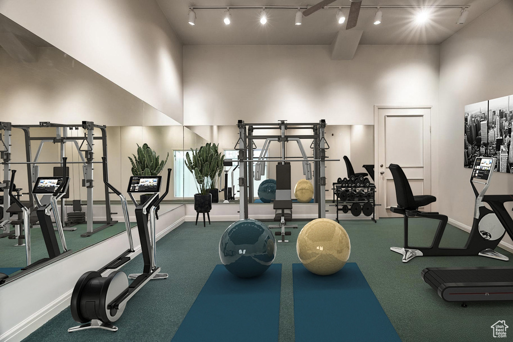 Gym with rail lighting, a high ceiling, and baseboards