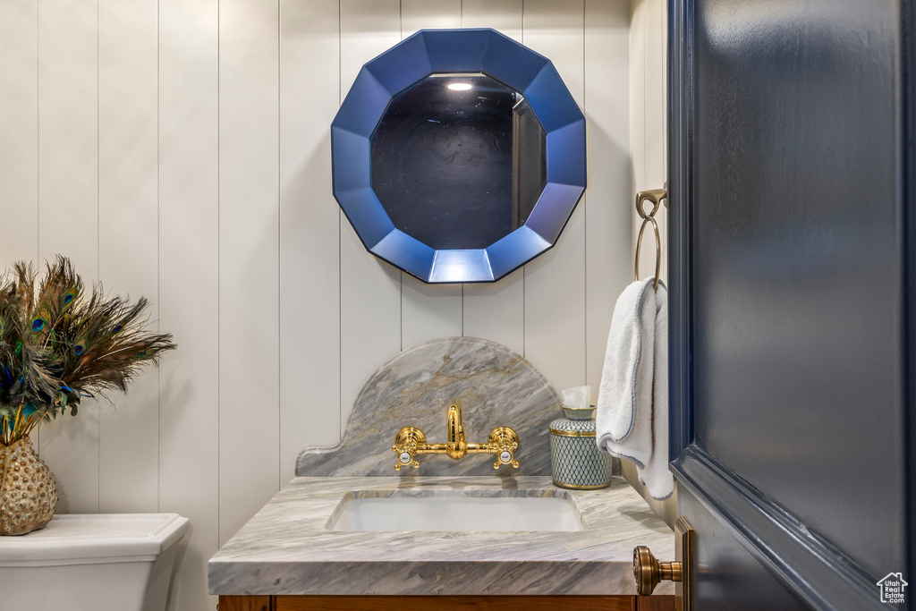 Bathroom view of toilet, a decorative wall, and vanity
