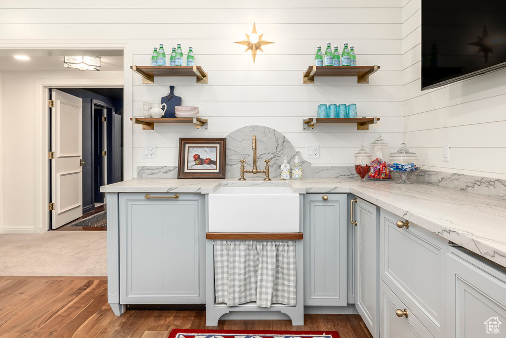 Kitchen with open shelves, wood finished floors, light stone counters, and wooden walls