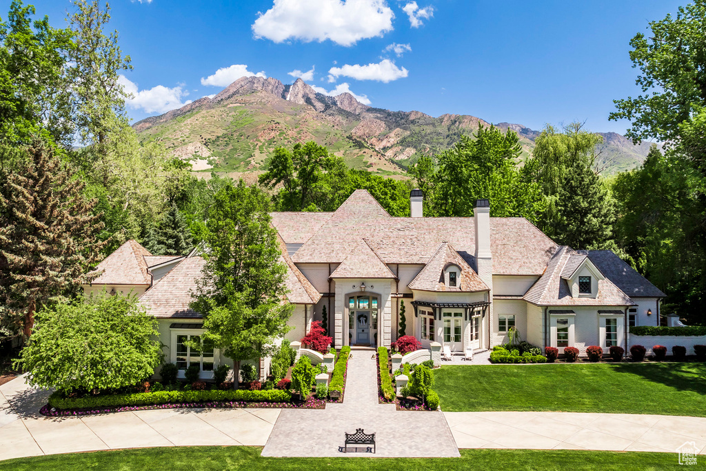 French provincial home with a chimney, stucco siding, a front lawn, french doors, and a mountain view