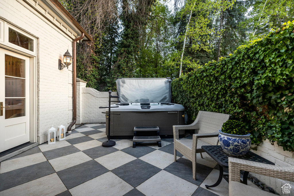View of patio with a hot tub and fence