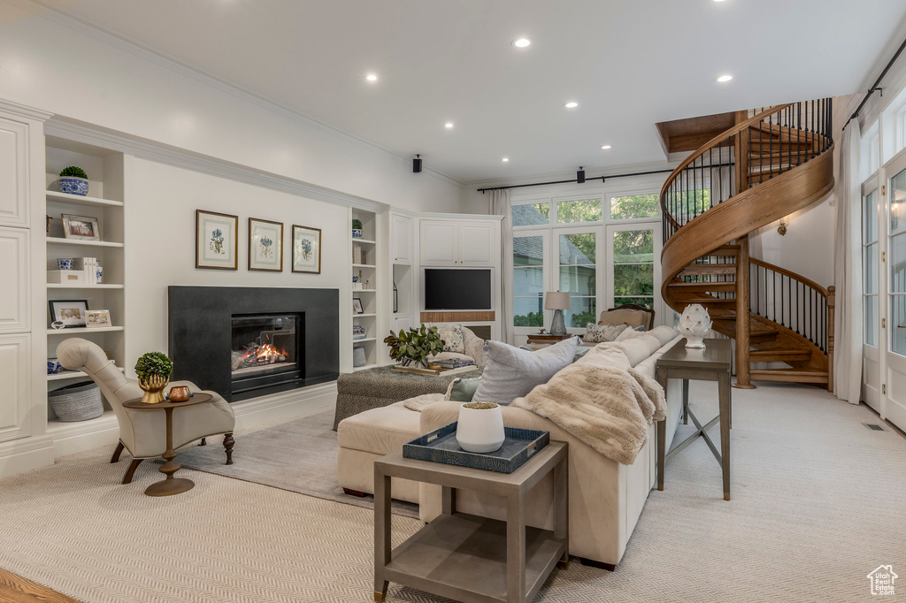 Living room featuring stairs, built in features, a glass covered fireplace, recessed lighting, and light carpet