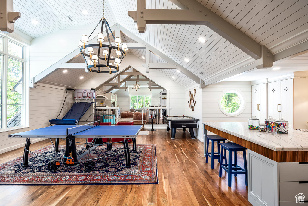 Playroom featuring wood finished floors, healthy amount of natural light, a chandelier, wood walls, and billiards table