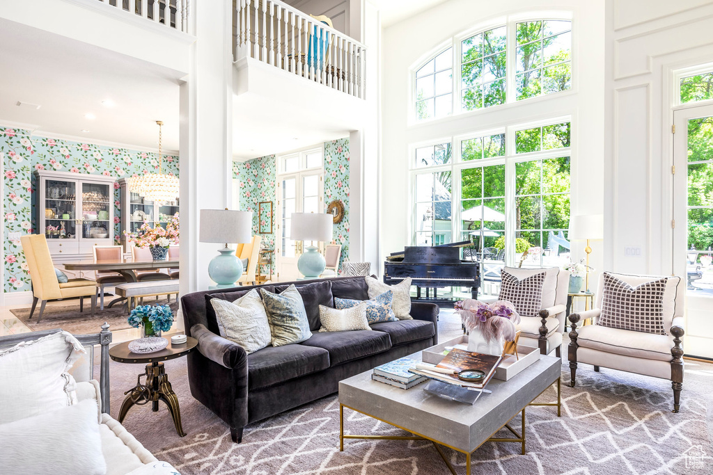 Living room with healthy amount of natural light, a towering ceiling, and wallpapered walls