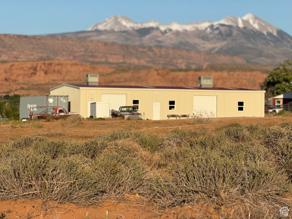 Back of house featuring a mountain view, an outbuilding, a pole building, and a garage