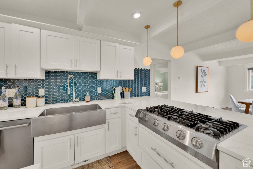 Kitchen with stainless steel appliances, beam ceiling, a sink, tasteful backsplash, and white cabinetry
