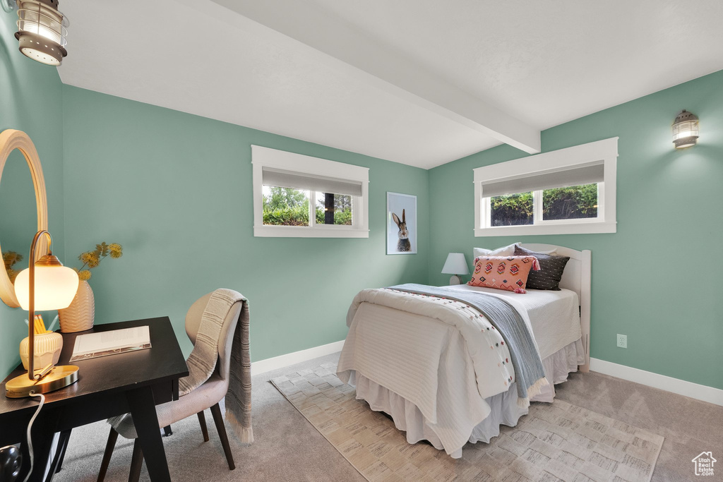 Bedroom featuring multiple windows, light carpet, beam ceiling, baseboards, and a desk