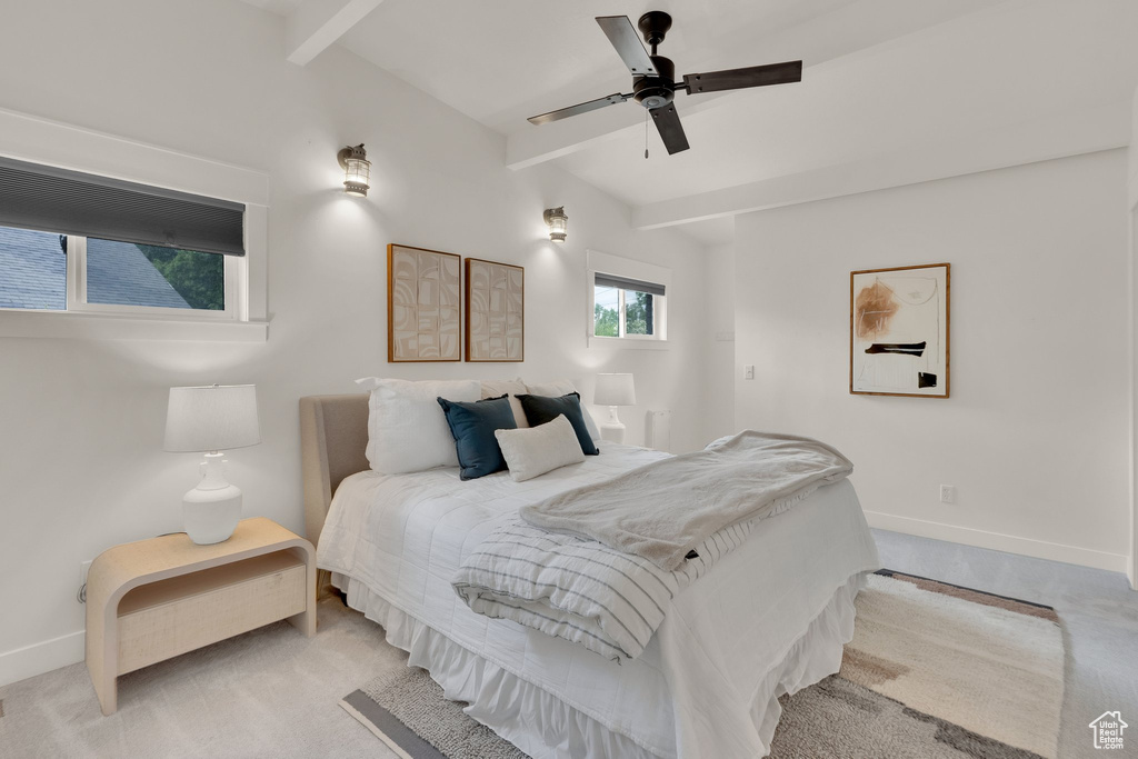 Bedroom featuring beamed ceiling, baseboards, light colored carpet, and a ceiling fan