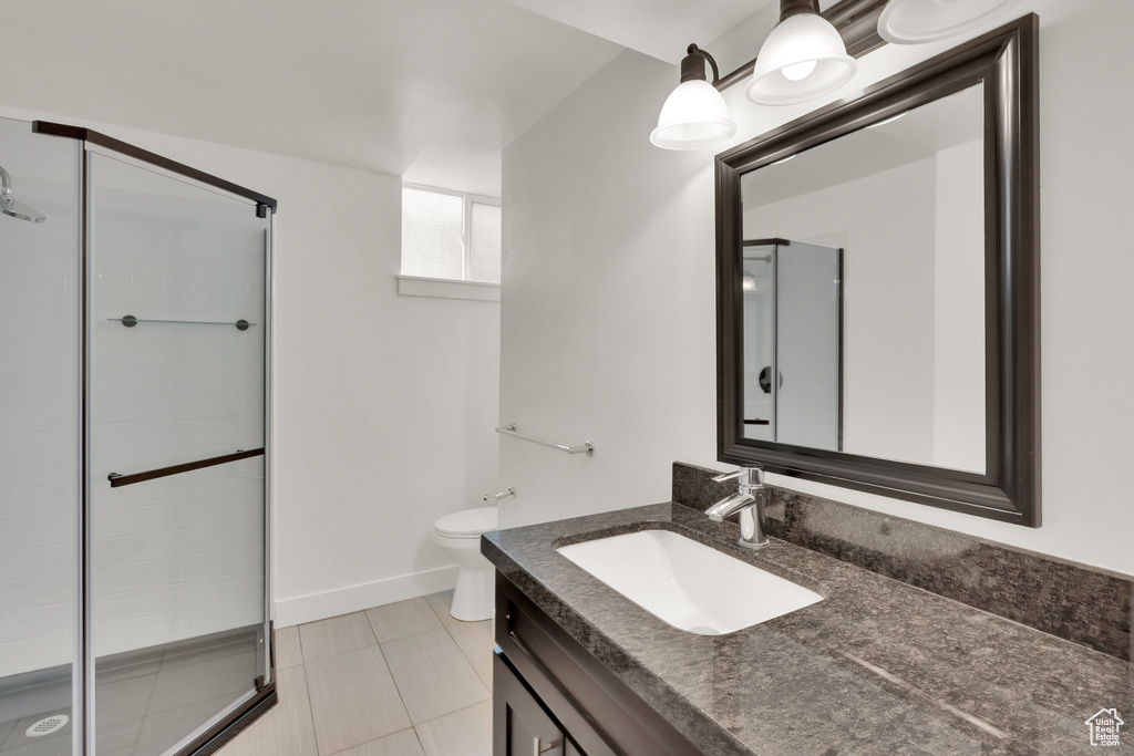 Bathroom featuring a stall shower, toilet, vanity, tile patterned flooring, and baseboards