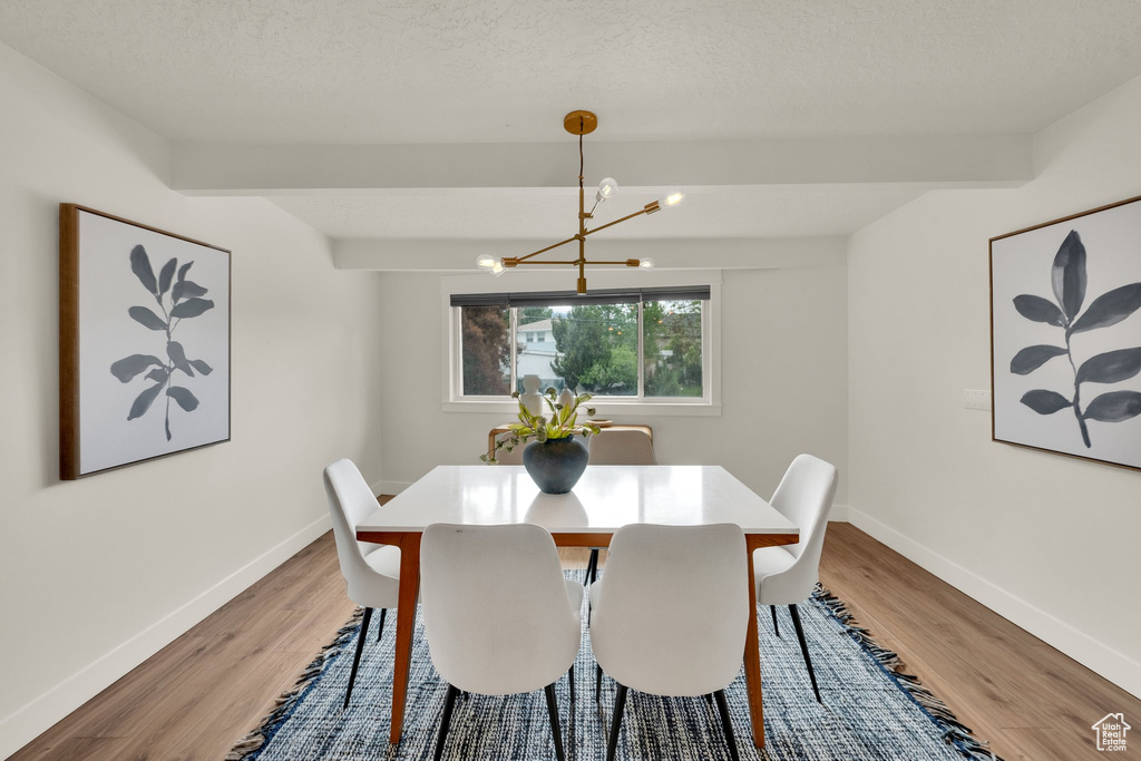 Dining room with a chandelier, light wood-type flooring, and baseboards