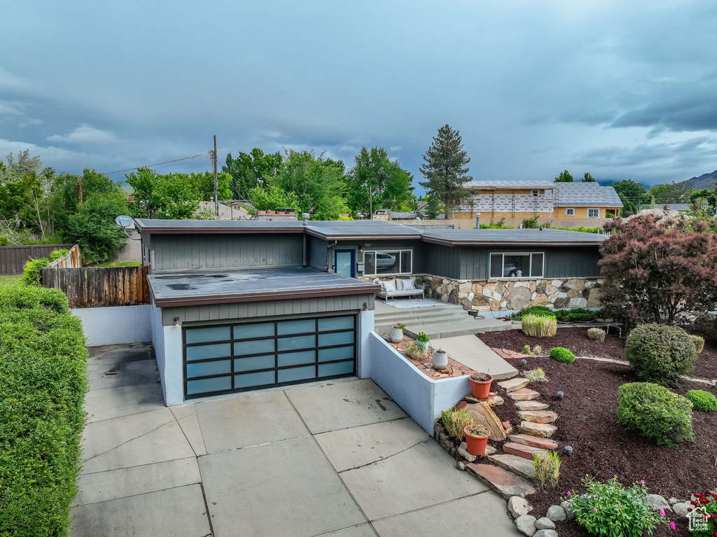 Mid-century inspired home featuring a garage, fence, and driveway