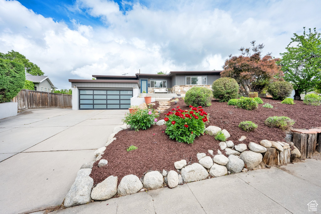 View of front facade featuring an attached garage, concrete driveway, fence, and stucco siding