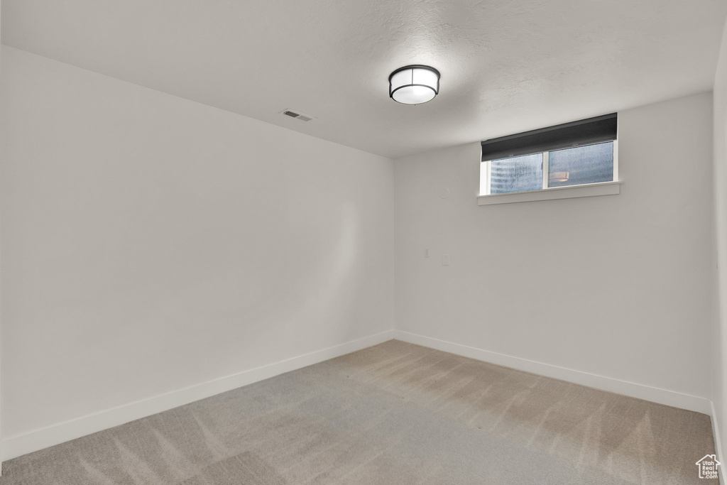 Spare room featuring light carpet and baseboards