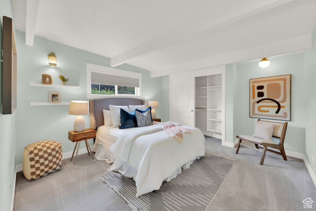 Carpeted bedroom with beam ceiling, baseboards, and a closet