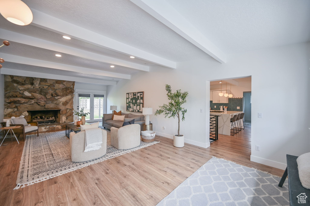Living area featuring wood finished floors, baseboards, recessed lighting, beam ceiling, and a fireplace
