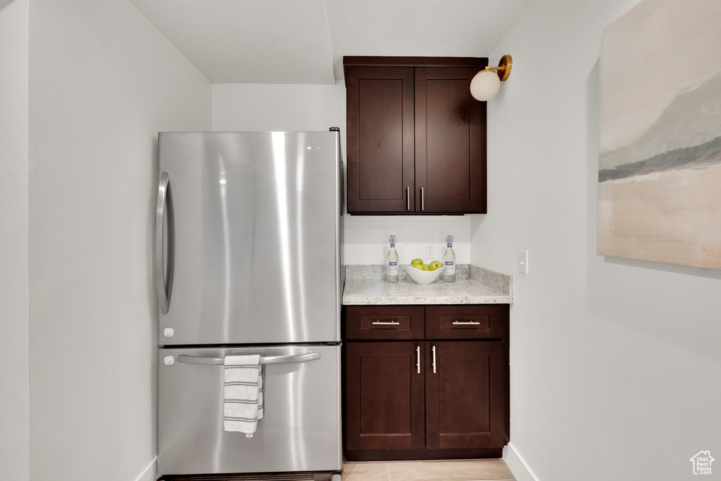 Kitchen with freestanding refrigerator, baseboards, and dark brown cabinetry