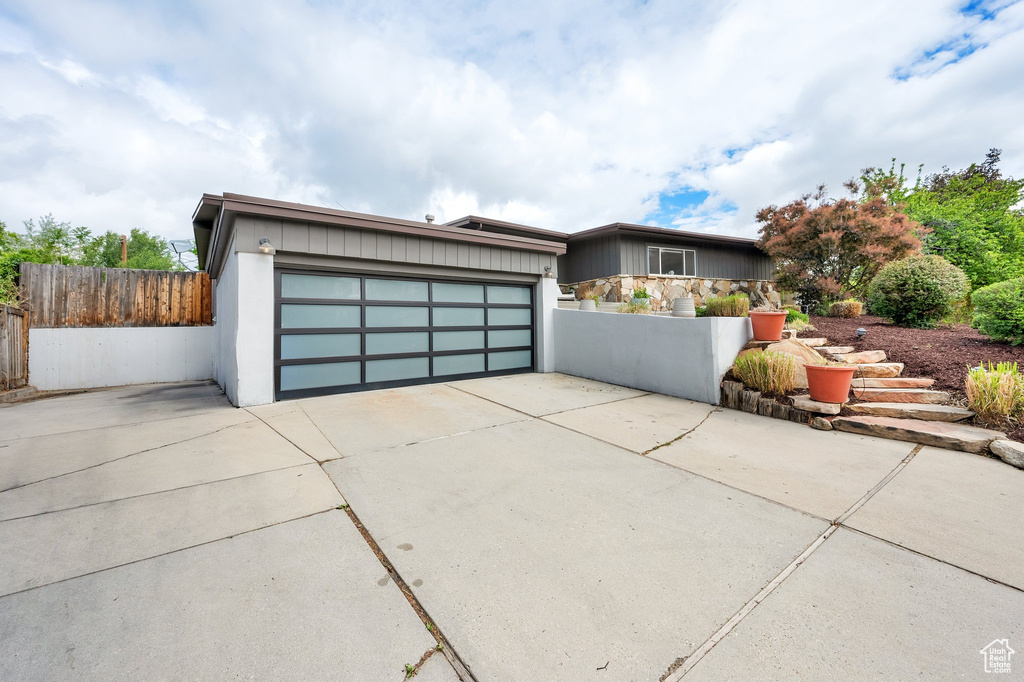 View of front of home with fence, driveway, and a garage