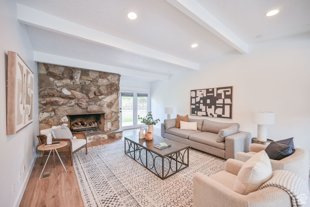 Living area with beam ceiling, light wood-style floors, recessed lighting, a fireplace, and baseboards