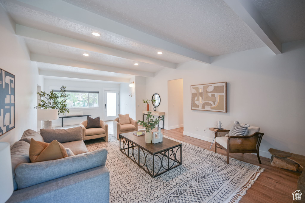 Living area with beamed ceiling, recessed lighting, wood finished floors, baseboards, and a textured ceiling
