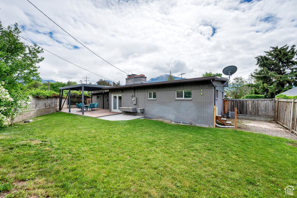 Back of house with a chimney, a patio, and brick siding