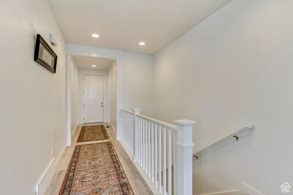 Corridor with inlaid floor details, an upstairs landing, recessed lighting, and baseboards