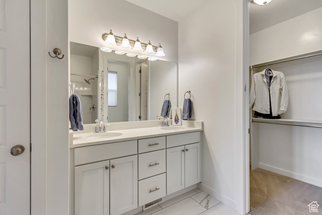 Full bath featuring a shower, baseboards, and double vanity