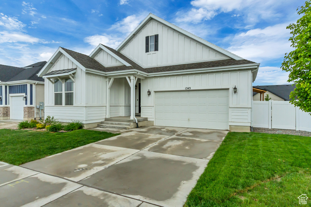 View of front facade featuring board and batten siding, driveway, a garage, and a shingled roof