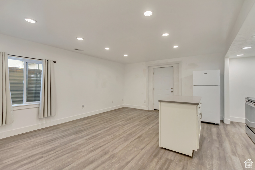 Kitchen with freestanding refrigerator, a center island, light wood-style floors, recessed lighting, and baseboards