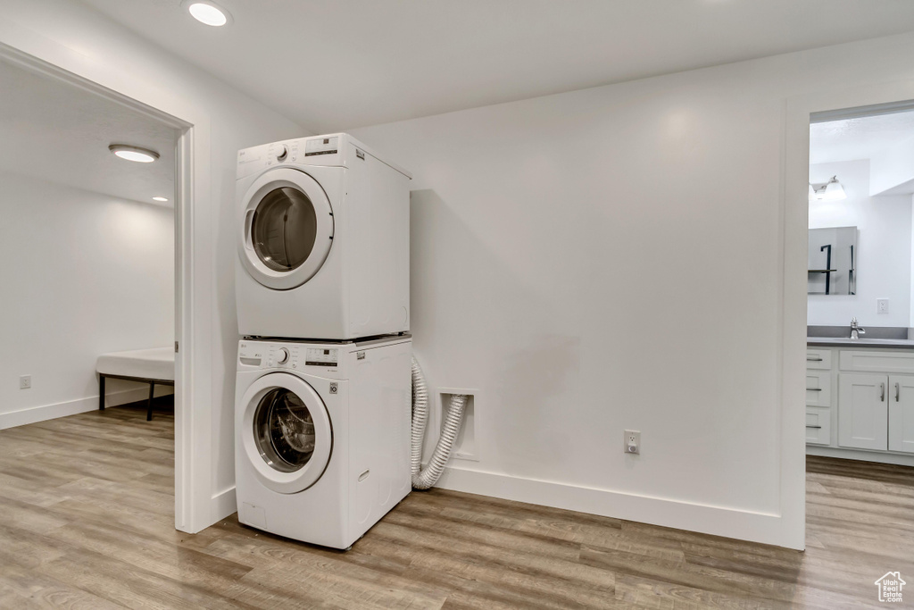 Clothes washing area featuring stacked washer / drying machine, light wood-style flooring, baseboards, and recessed lighting